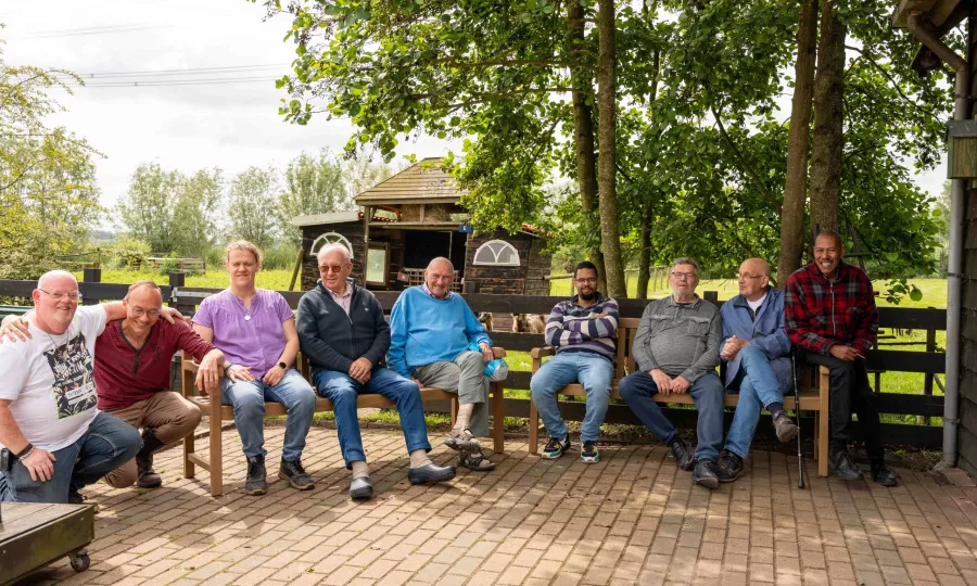 Deelnemers zorgboerderij Bonaventura zitten op de nieuwe banken. 