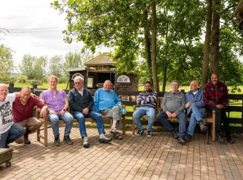 Deelnemers zorgboerderij Bonaventura zitten op de nieuwe banken. 